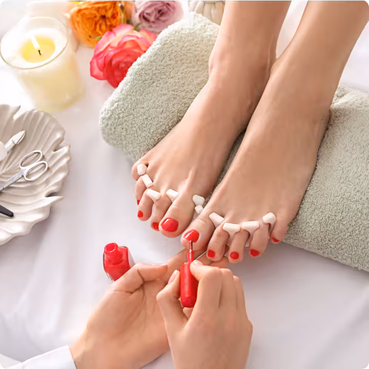 A nail technician polishes the client's toes.